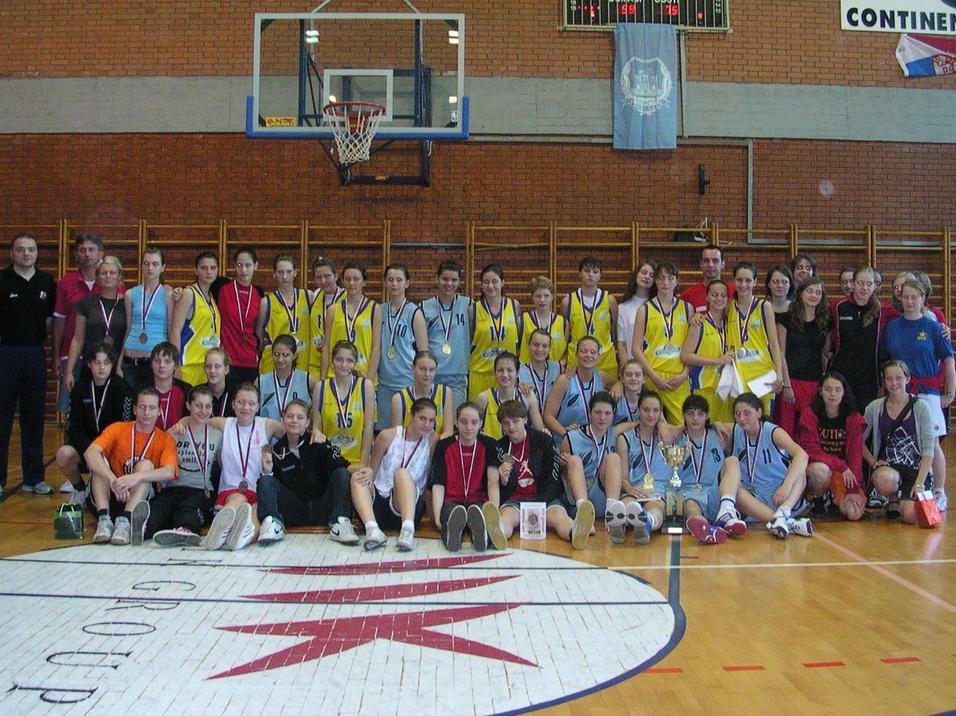 Novi Sad Gruppe von Basketballspielern in Trikots mit Medaillen auf dem Platz, umgeben von Trainern in einer Sporthalle.