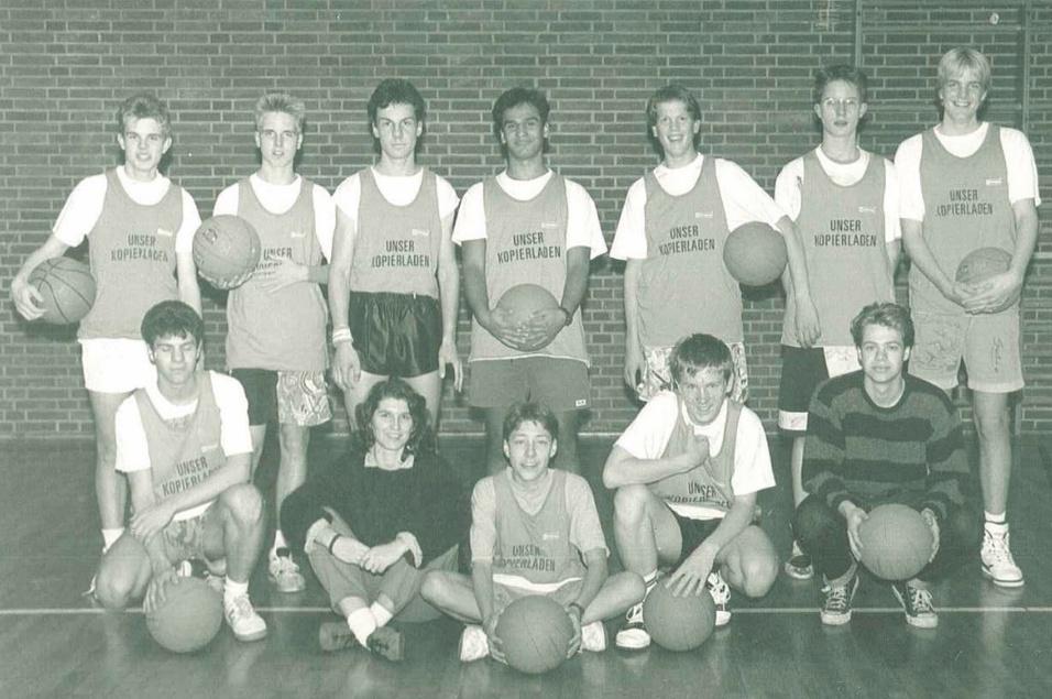 Jungs 1989 Eine Gruppe von zehn Basketballspielern in Trikots posiert auf einem Hallenboden, einige halten Bälle in den Händen.