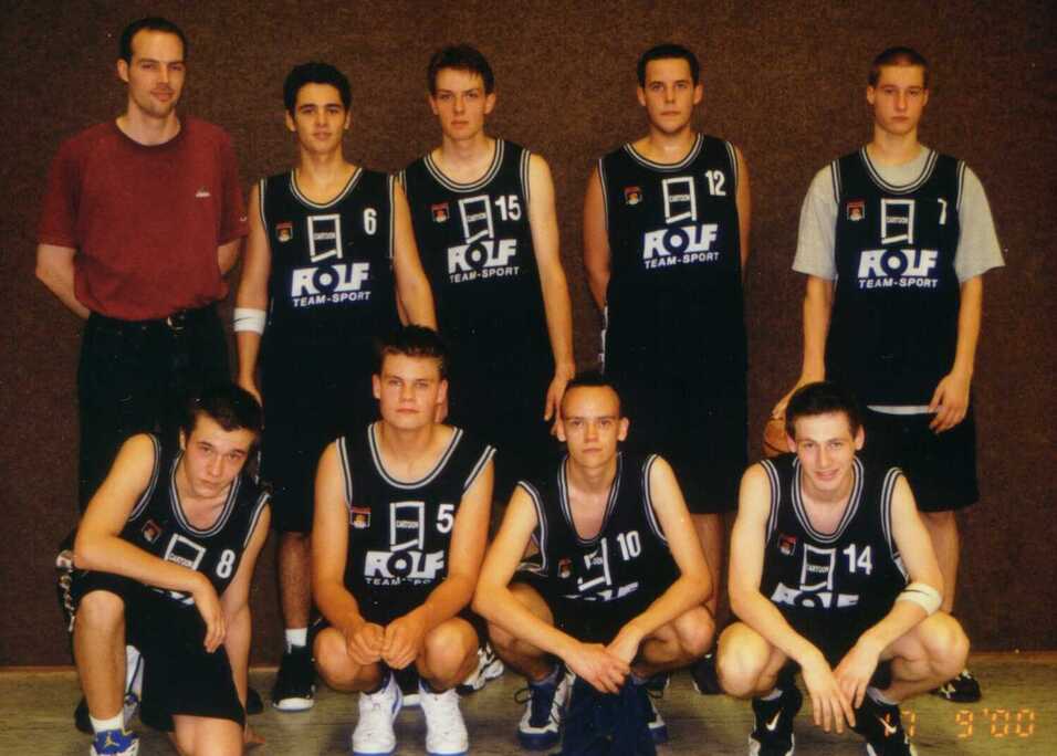 A-Jugend 2000/01 Mannschaftsfoto einer Basketballgruppe mit neun Spielern in Trikots und einem Trainer im Hintergrund.