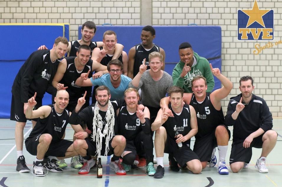 1. Herren 2016/17 Eine Gruppe von 13 Basketballspielern posiert jubelnd auf dem Spielfeld, einige halten einen Pokal und zeigen die Eins.