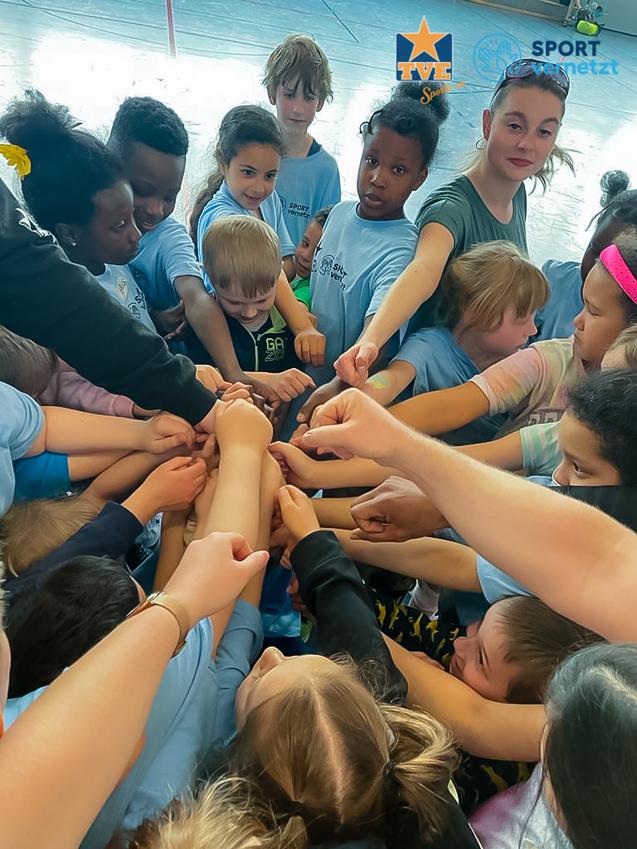 Integration SV Gruppierung von Kindern, die zusammen ihre Hände in die Mitte eines Kreises legen, auf einem Sportplatz.