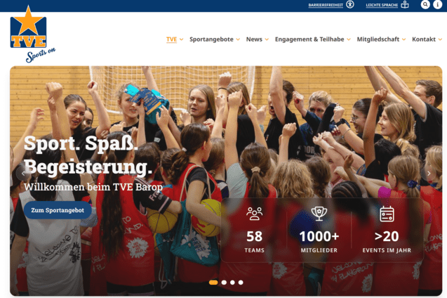 Gruppe von begeisterten Sportlerinnen jubelt gemeinsam in einem Sportzentrum mit Holzwänden.