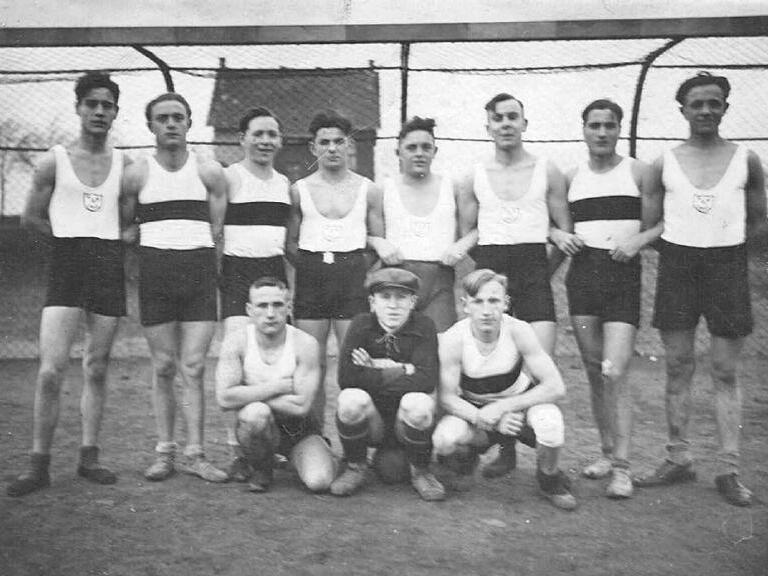 Schwarzwei&szlig;foto der TVE-Handballmannschaft um 1930, acht M&auml;nner in Sportanz&uuml;gen stehen und sitzen auf einem Platz.